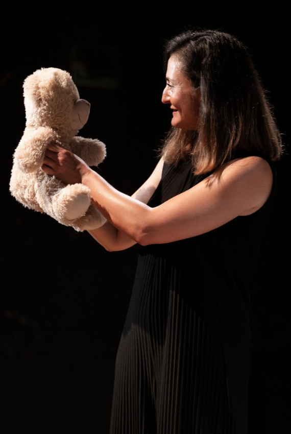 l'attrice sul palco guarda il suo orsacchiotto di peluches