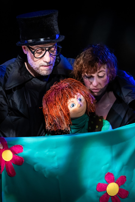 i due personaggi sul palco con una bambola dai capelli rossi