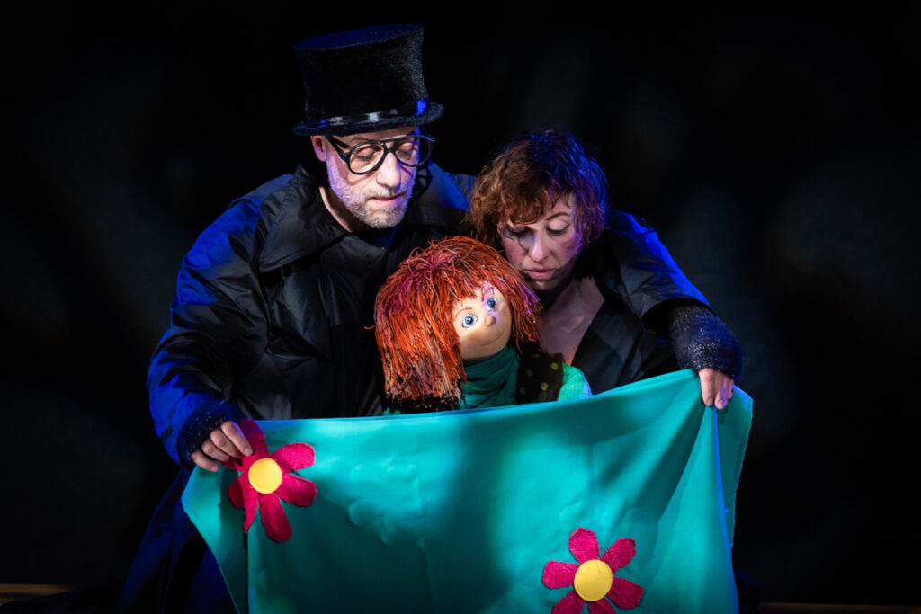 i due personaggi sul palco con una bambola dai capelli rossi