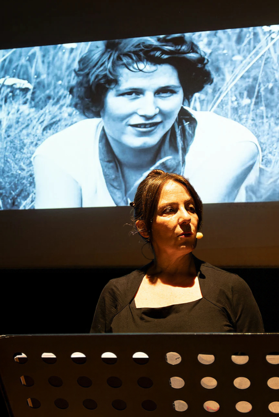 l'attrice racconta la vicenda mentre sullo sfondo vengono proiettate immagini storiche di tina merlin