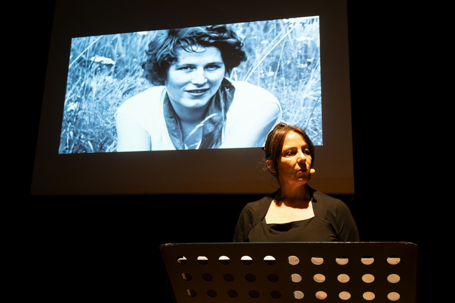 l'attrice racconta la vicenda mentre sullo sfondo vengono proiettate immagini storiche di tina merlin